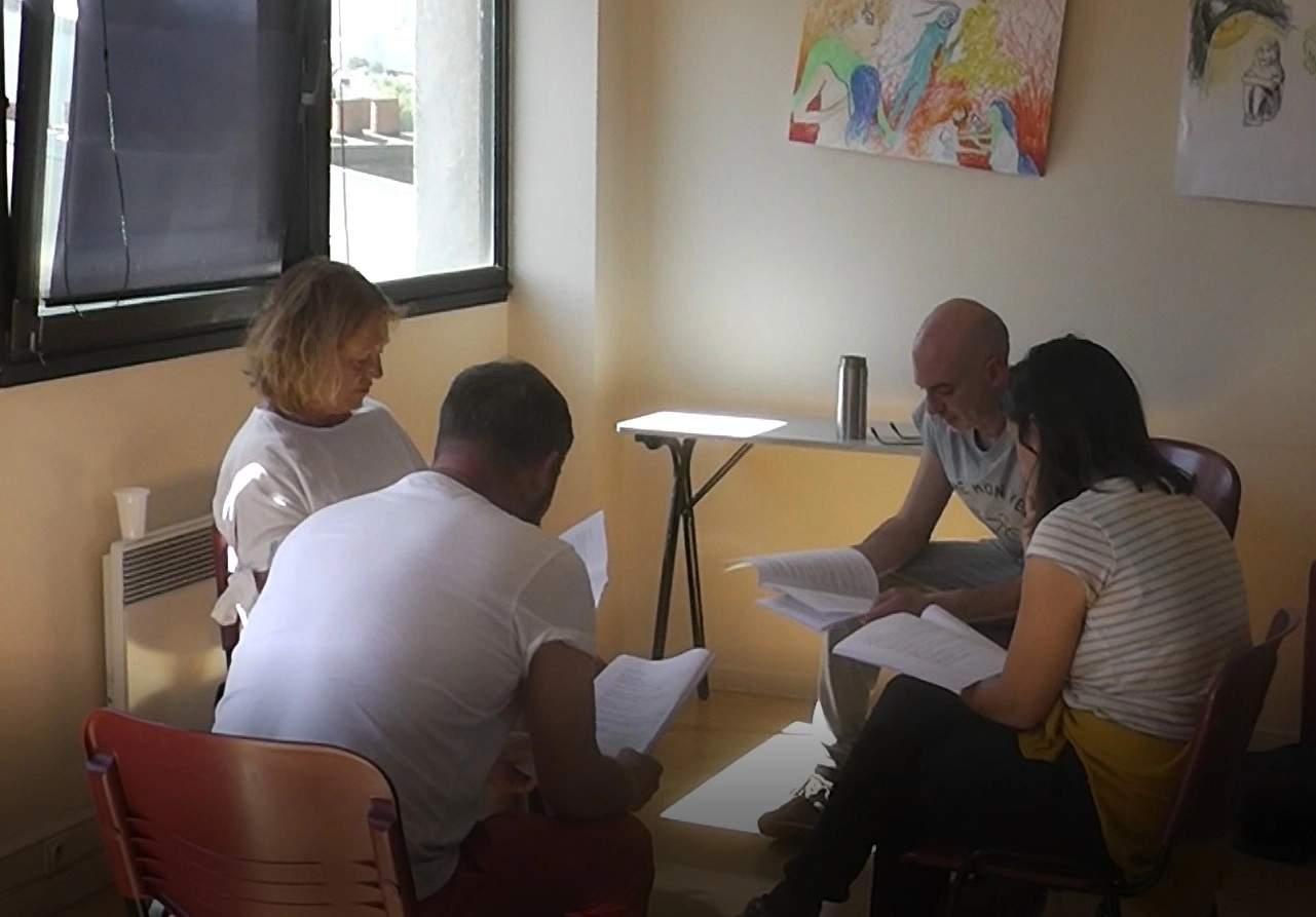 groupe de quatre assis, chacun regardant du texte sur un document